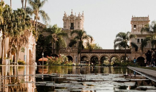 a building with a tower and trees by a body of water